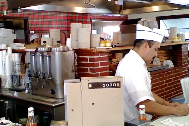 A counterman at the grill behind The Apple Pan's U-shaped counter